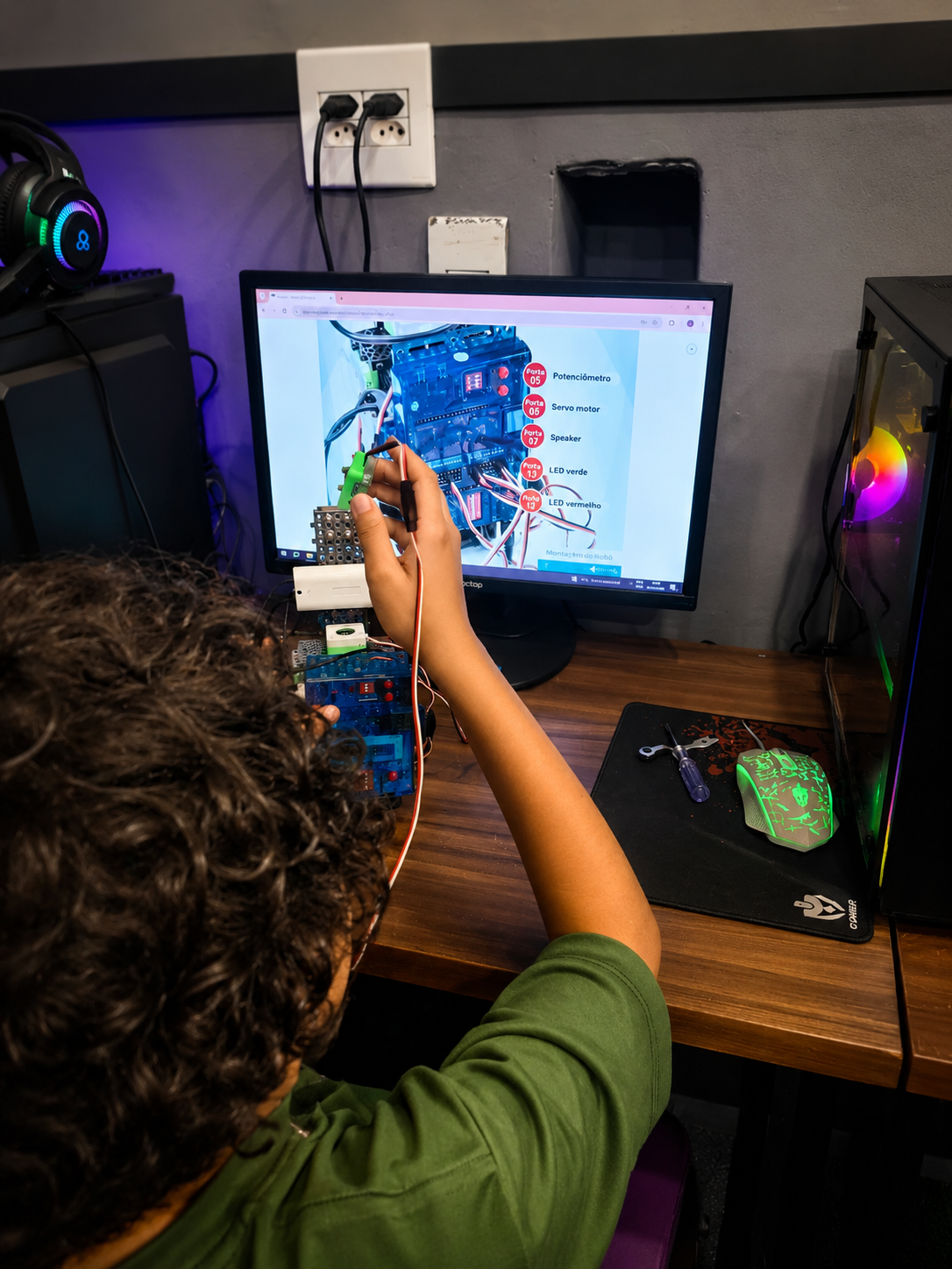 Aluno montando robô com sensores e LEDs em aula de robótica